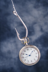 Pocket watch hanging on fish hook. Time trap concept, idea of time management addiction