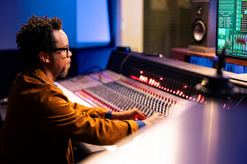 Audio expert processing music from soundproof vocal booth at professional studio, recording songs...