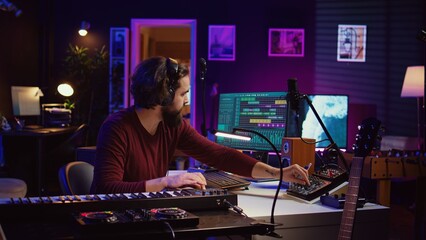 Sound engineer operates recording equipment and oversees audio performances to ensure the perfect notes. Musician composer producing sounds with MIDI controller and mixing console. Camera B.