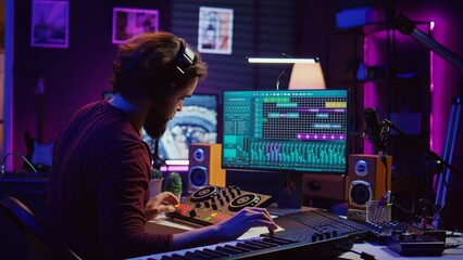 Artist improving the sound quality of audio recordings in home studio, handling mixing console and controls. Producer uses his creative vision to manipulate sounds, audio equipment. Camera B. © DC Studio