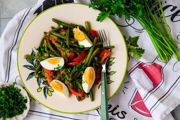 Warm vegetable salad with green beans and boiled eggs on a plate with an ornament..top veiw.selective focus