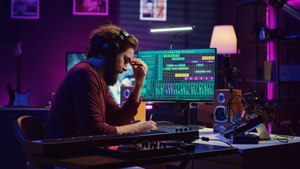 Musician artist taking notes composing new song in his home studio, writing down lyrics and musical notes before recording his melody. Songwriter producing music with daw software tools. Camera A.