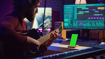 Beginner singer learning to play and tune his acoustic guitar, watching tutorial lesson practice...