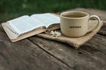 Cup with text BLESSED and open Bible in the garden, good morning