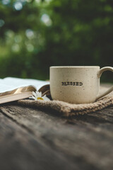Cup with text BLESSED and open Bible in the garden, good morning