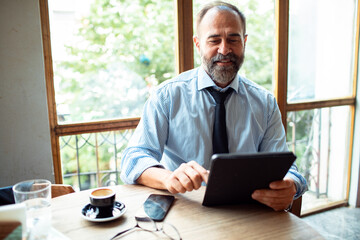Businessman in a cafe working with tablet and drinking coffee