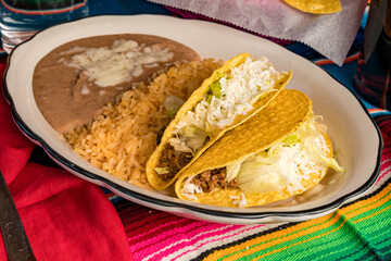 Two hard shell tacos with refried beans and rice