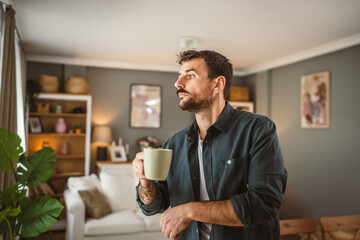 Portrait of adult handsome man drink first coffee in the living room