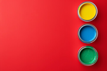 Banner with four cans of colorful paint on a red empty background with space for text or inscriptions, top view
