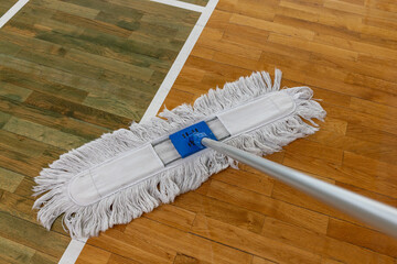 Cleaning Mop on Wooden Floor with Court Lines in Gymnasium or Sports Hall