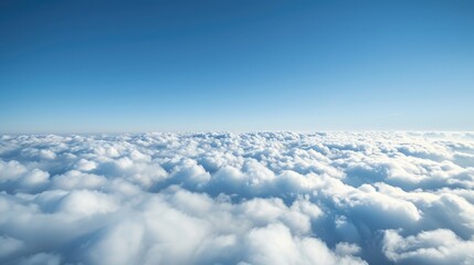 Bird s eye view over a blanket of clouds under a clear blue sky