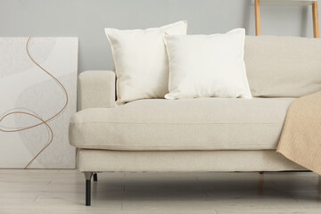 Soft white pillows and blanket on sofa indoors