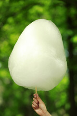 Woman holding sweet cotton candy outdoors, closeup