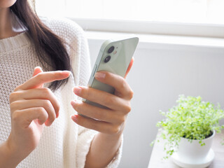 スマートフォンを操作する女性と清潔感のある部屋