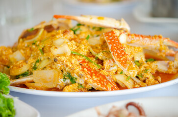 Blue Crab in Curry Powder  is a vibrant Thai dish with tender crab in a creamy, aromatic yellow curry sauce, mixed with bell peppers and onions. A visually appealing and flavorful seafood delight.