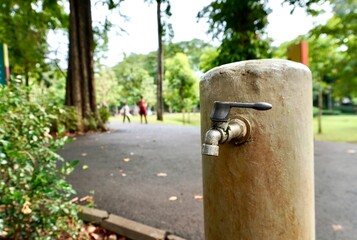 Metal iron or stainless steel material tap water faucet isolated on horizontal ratio outdoor fresh eco green park environment background.