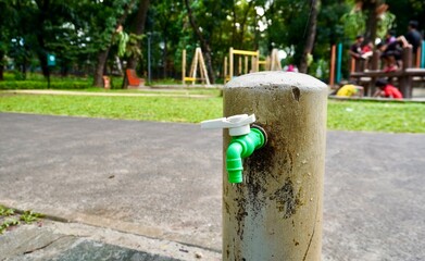 White and green plastic material tap water faucet isolated on horizontal ratio outdoor fresh eco green park and playground environment.