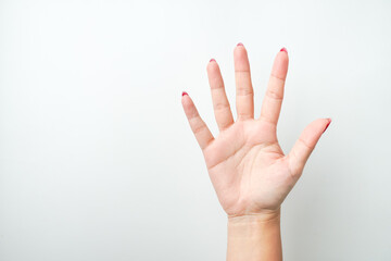 A woman's hand with bright red nail polish is making a raising open hand gesture. Isolated on white background - Cut Out