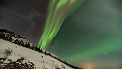 Northern lights aurora seen outside of Whitehorse in Yukon Territory, Canada during winter time with snow covered landscape