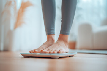 Closeup of feet, Young Asian woman standing on scales to measure her weight at home, Checking...