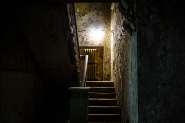 Exit from the basement to the stairs in an old gloomy building, exploring abandoned houses