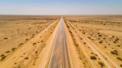 Fototapeta premium Long straight road stretches across a desert landscape
