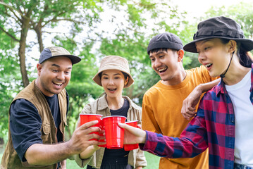Happy asian diverse group friends enjoy drinking a beer together. They feeling relaxed and refreshing while camping in the nature at night. Recreation and journey outdoor activity lifestyle.