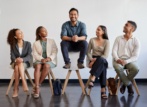 Happy, business people and waiting room with chair for hiring, career or job opportunity at office. Group of employees with candidate standing out on furniture in recruiting for selection or pick