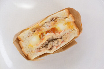 the left rotate view close-up image of the tuna sandwich with a runny egg