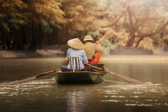 Tam Coc village boat tour in Vietnam. Man and a women rowing the Tam Coc river.