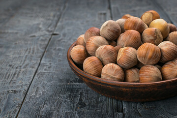 Rustic Wooden Bowl Filled with Raw Hazelnuts Resting on Weathered Wooden Table
