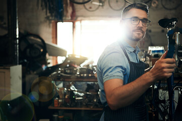 Man, portrait and bicycle mechanic with inspection for fix or maintenance at repair shop. Young male person or expert working on bike parts with tools or equipment for service at workshop or garage