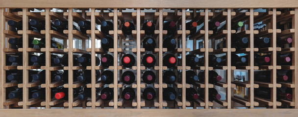 Bottles of wine on wooden shelf, in winery store