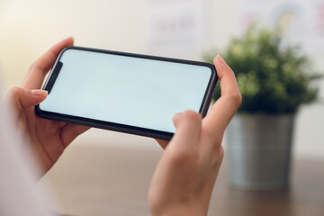 Hand holding smartphone mockup of blank screen for graphic display montage.