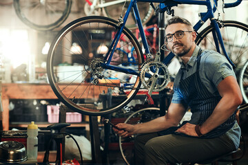 Man, portrait and fixing at work in bicycle repair shop or maintenance garage. Bike, mechanic and service with a professional handyman for startup, small business and mechanical vehicle workshop