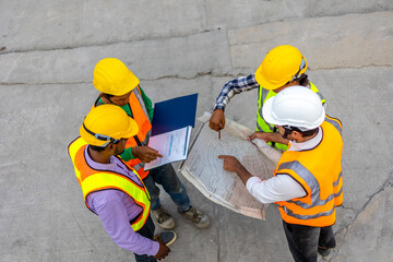 Top view of a group of civil engineers discussing their plan using factory blueprint