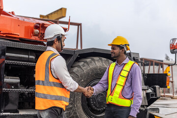 Two civil engineers from different cultures reach partnership agreement and have handshake in a construction factory