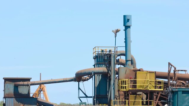 Industrial equipment in scrapyard recycling material delivered by dump trucks
