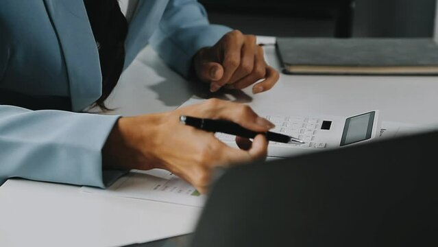 Close up Business woman using calculator and laptop for do math finance on wooden desk in office and business working background, tax, accounting, statistics and analytic research concept
