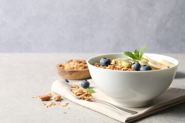 Tasty granola with fresh fruits on grey table