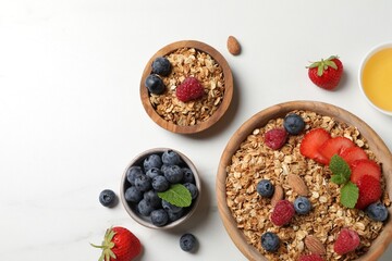 Tasty granola with berries, nuts and mint on white table, flat lay