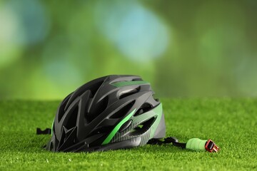 Stylish protective helmet on green grass against blurred background