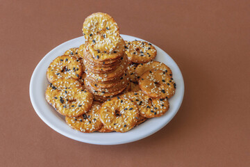 A pile of salted round pretzels with black and white sesame on a plate