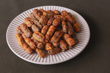 Sweet, spicy tamarind tree fruit in a round plate on a dark background