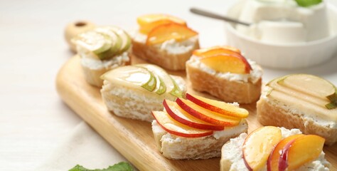 Delicious ricotta bruschettas with pears and apricots on white table, closeup