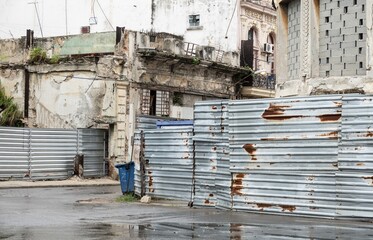 Corrugated galvanised iron fence, neglected buildings in Havana, Cuba