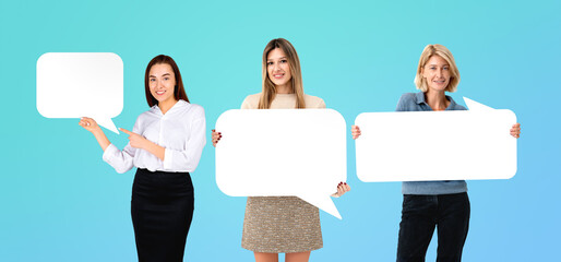 Three women holding blank speech bubble signs on a light blue ba
