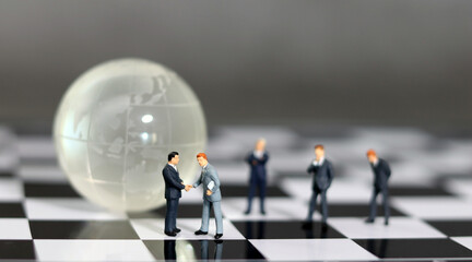 Miniature entrepreneurs shaking hands against a globe background.  The concept of partnership.  The...