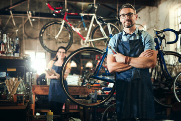 Man, portrait and arms crossed at bicycle repair shop for work in maintenance garage. Bike, mechanic and service with woman handyman coworker for startup, small business and workshop for fixing