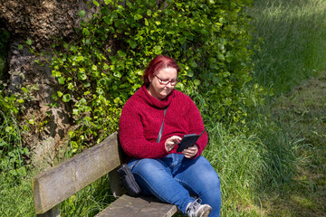 Obraz premium Woman reading a message on the phone in the park